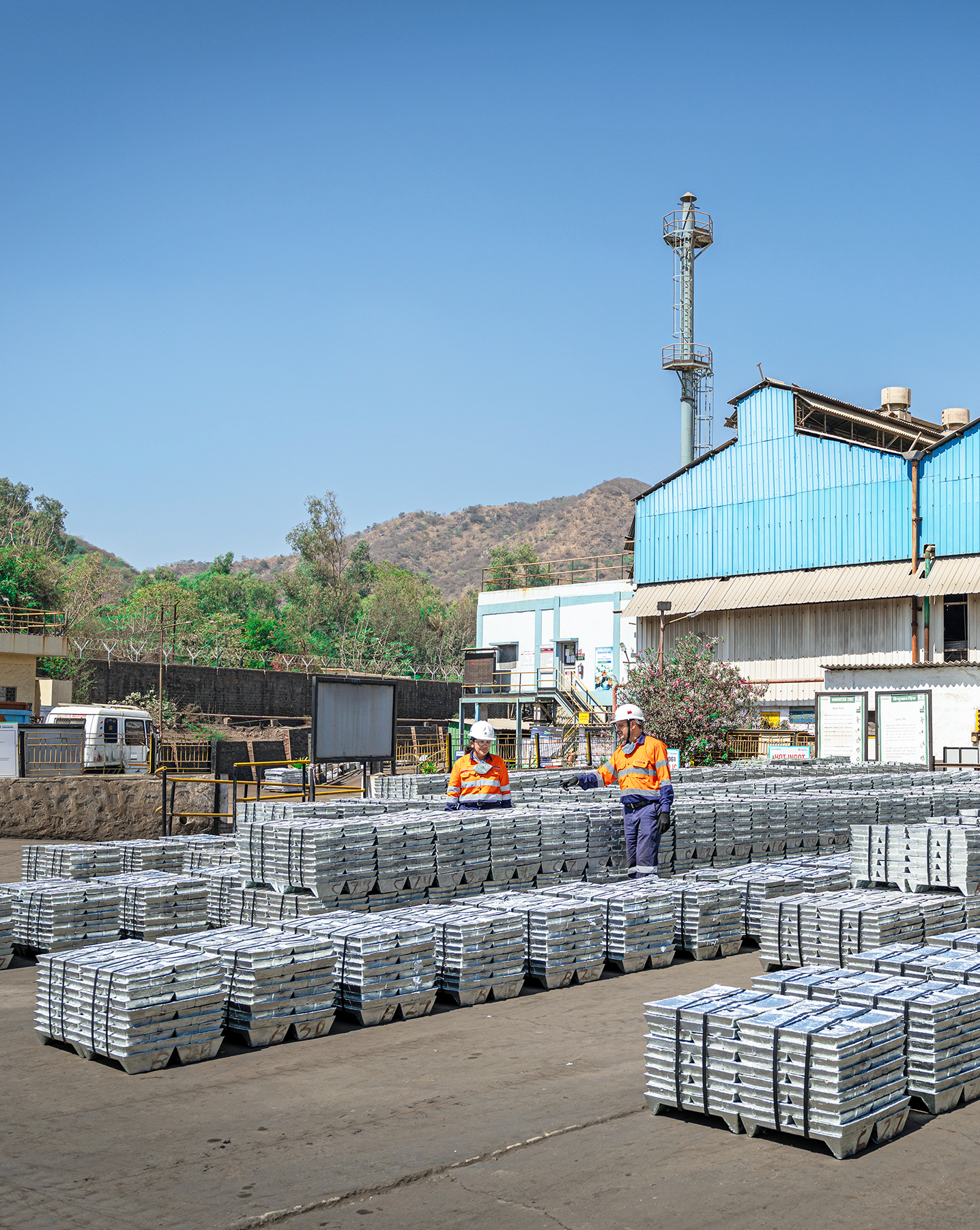 Workers inspecting rows of zinc ingots at a smelting complex